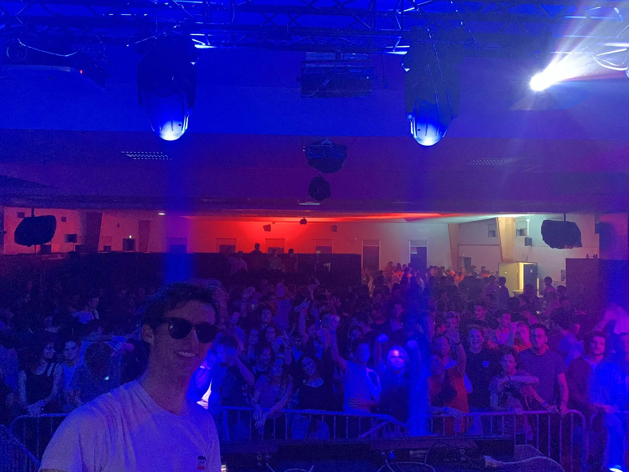 Louis, DJ et cofondateur de Baska Events, devant une salle comble éclairée en bleu et rouge pendant une soirée étudiante