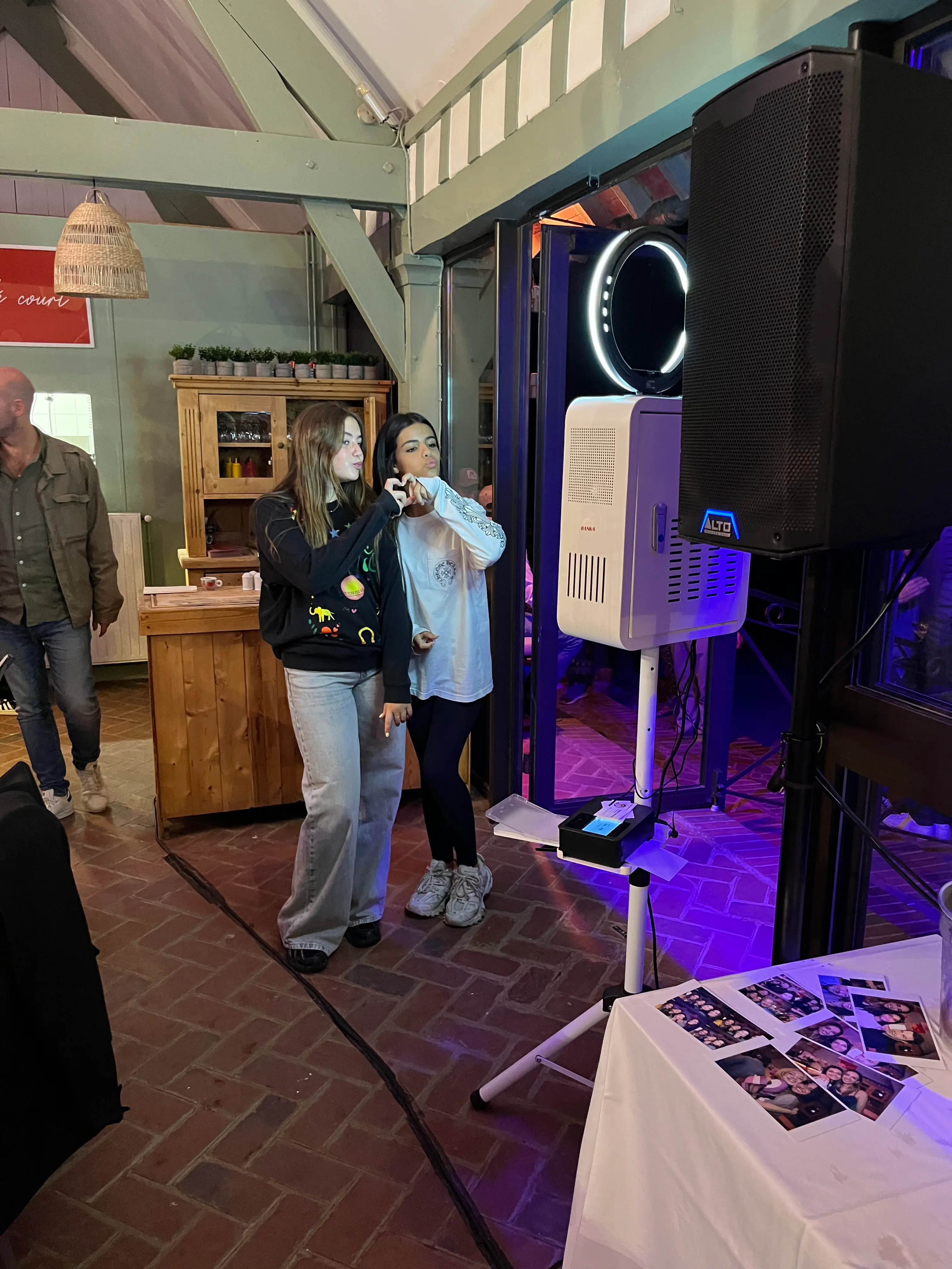 Deux invitées se prennent en photo devant une borne photobooth à anneau lumineux, à côté d'une enceinte sur pied, pendant une soirée